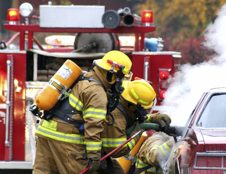Firemen around a burning car
